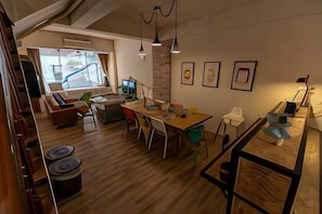 Un interior moderno con comedor, sofá, escalera y vistas al exterior.