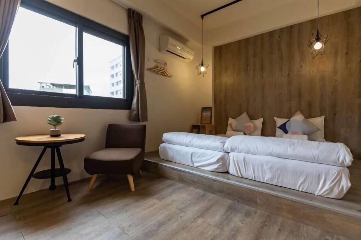 Een kamer met een bed, een stoel, een tafeltje en een raam.