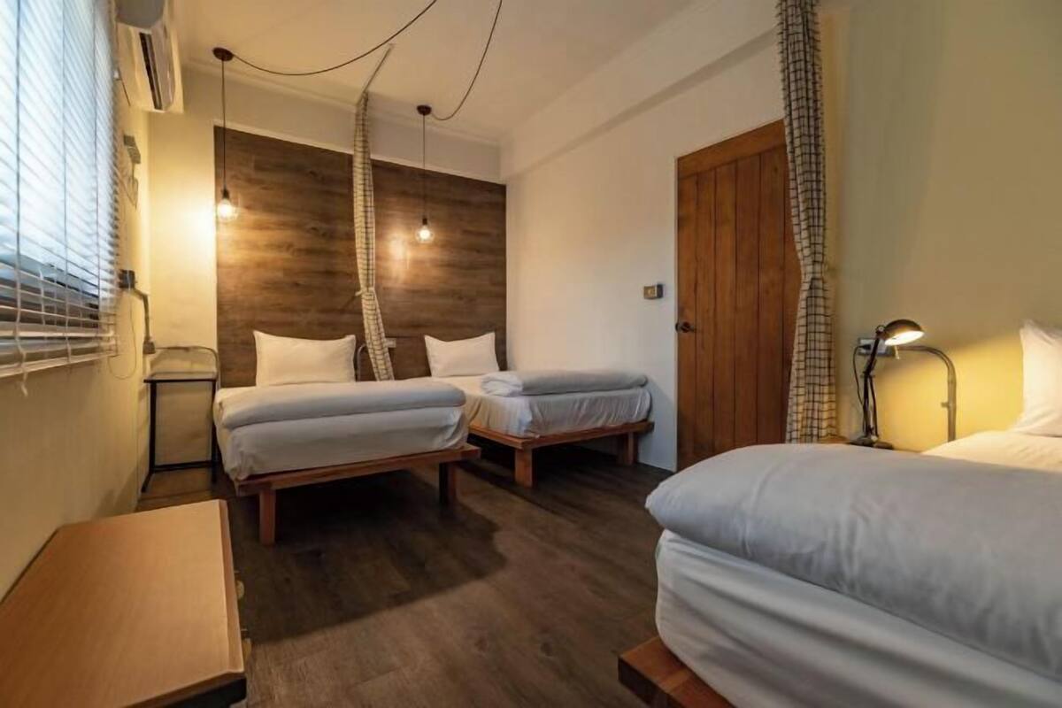 Een hotelkamer met twee eenpersoonsbedden, een houten accentmuur, een houten deur en een kleine tafel.