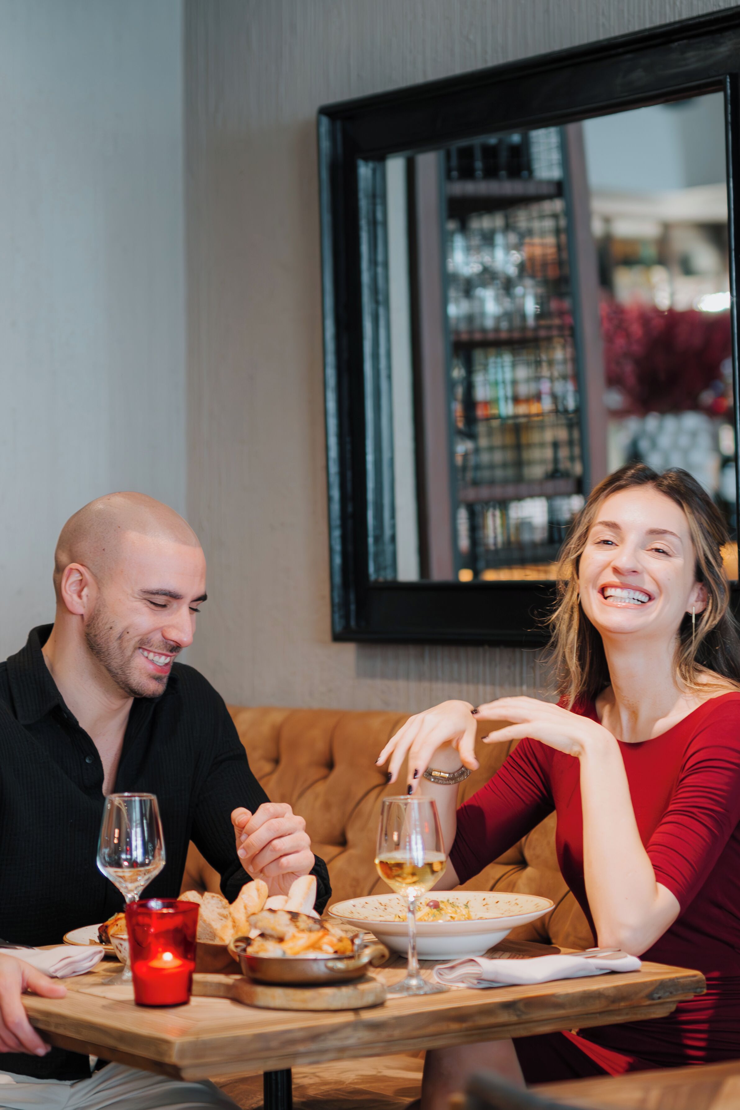 Una mesa de comedor con una vela, copas de vino y comida.