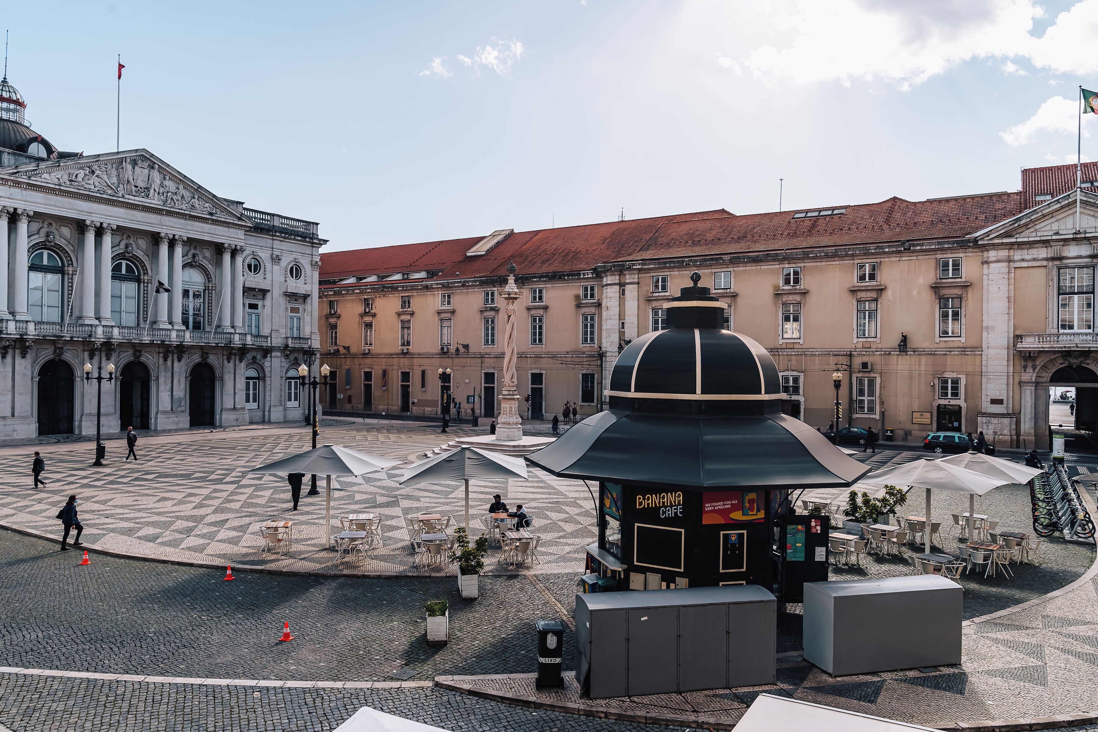A public square with a café, a historical building, and a fountain.