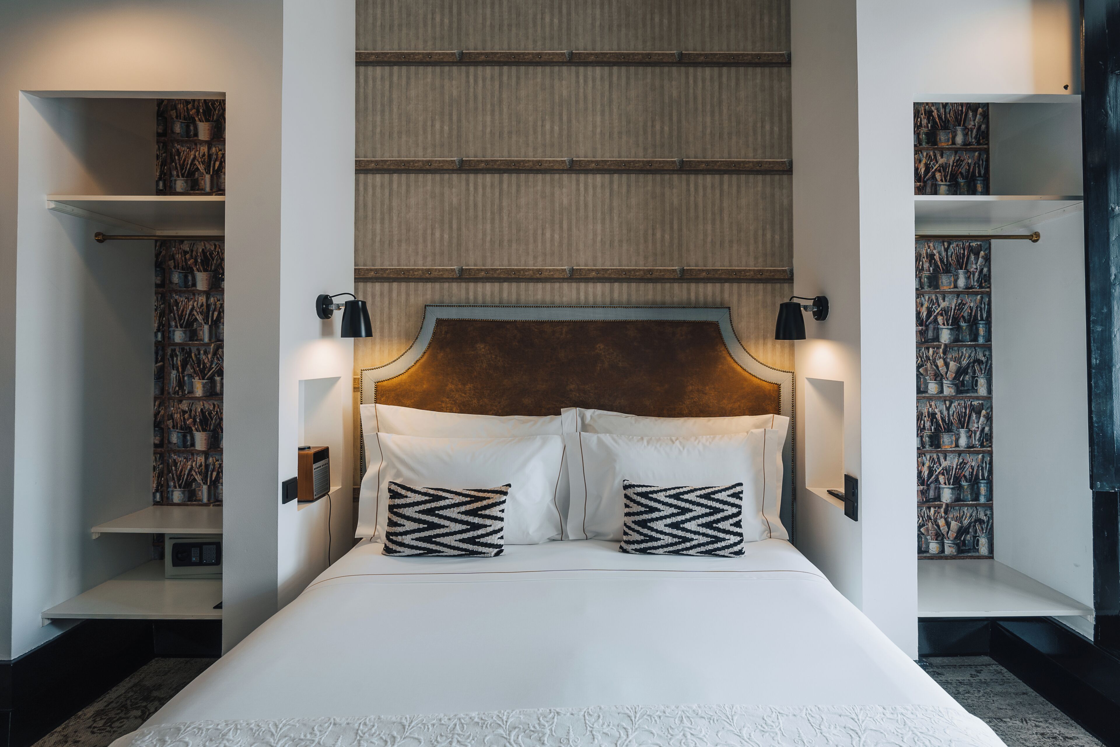 A neatly made bed with a wooden headboard, two bedside lamps, and decorative pillows.
