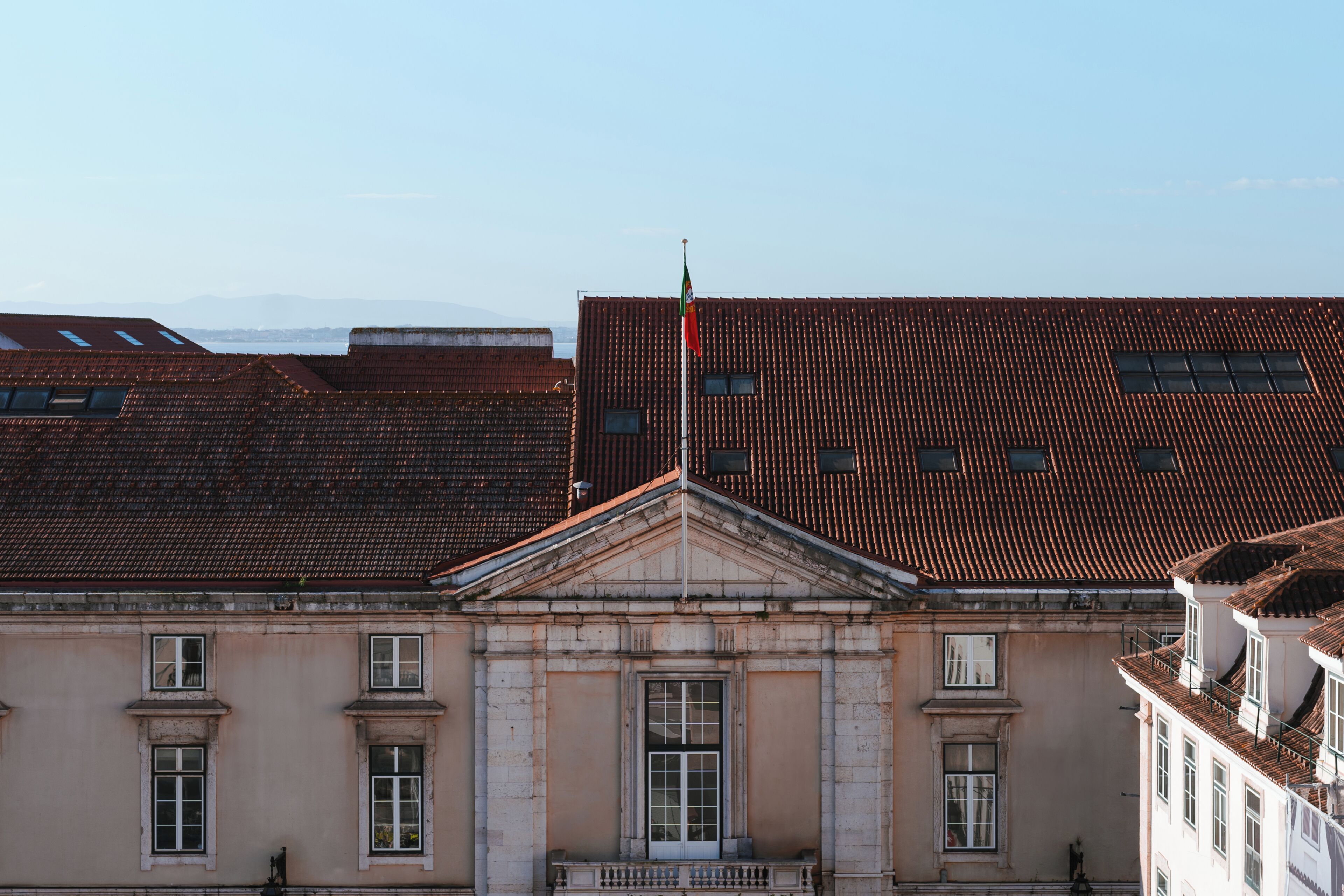 A building with a classical facade, a prominent flagpole, and a symmetrical window arrangement.