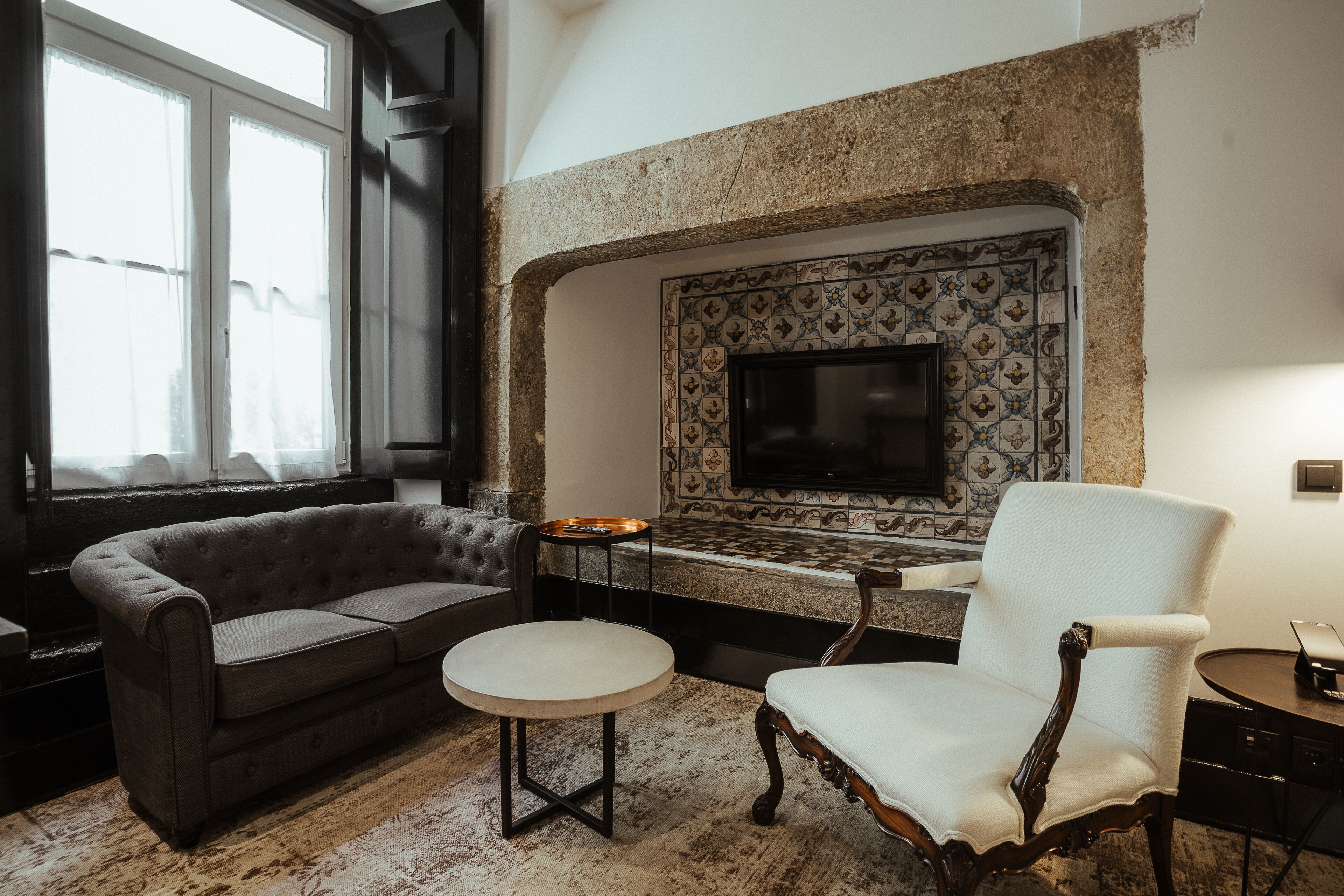A living room with a fireplace, a sofa, a chair, and a small table.
