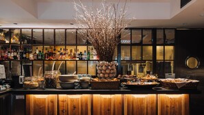 Un área de bar con mostrador de madera, diferentes alimentos y un adorno central con una rama decorativa.