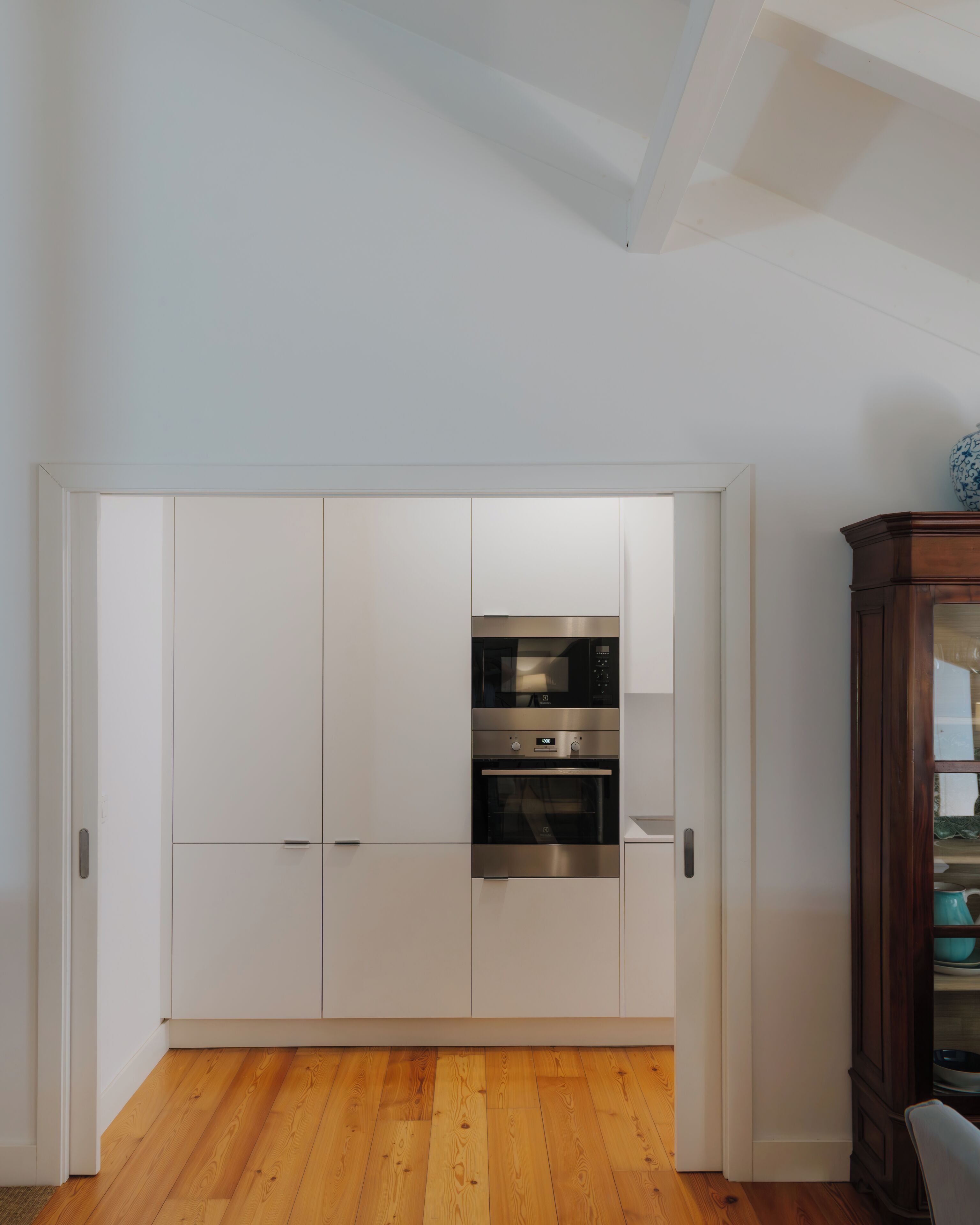 Una cocina moderna con armarios blancos, horno integrado y suelo de madera.