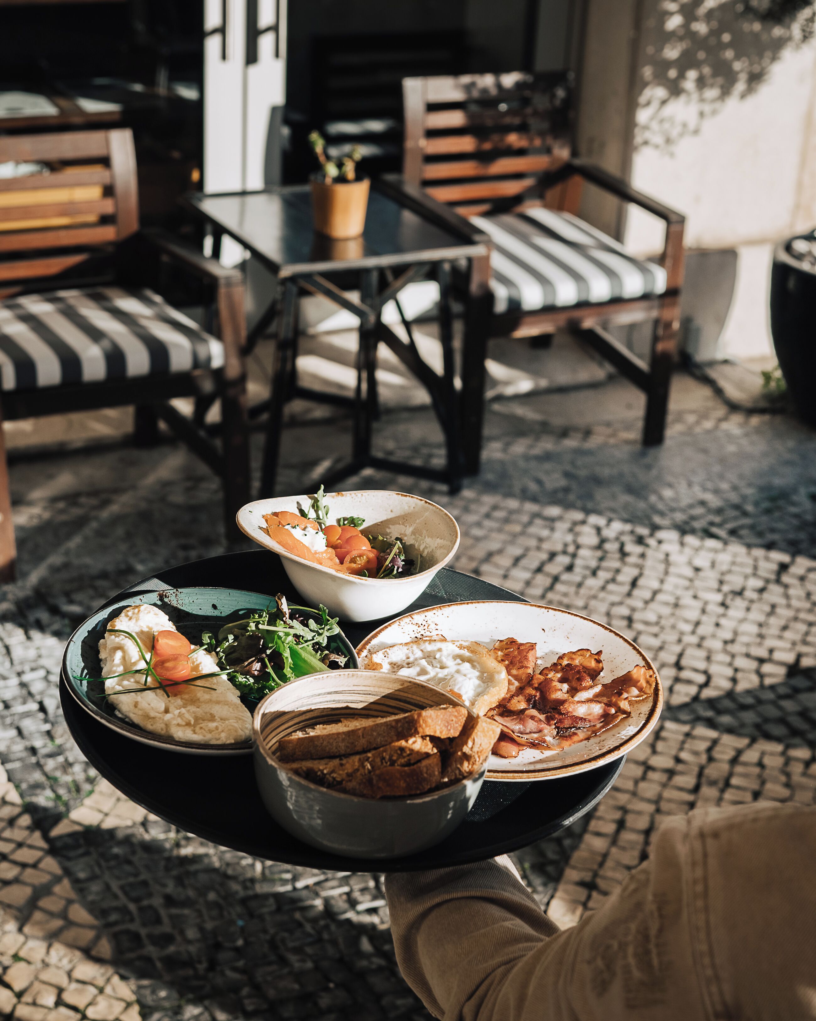 A tray with various dishes, a potted plant, and a chair with striped cushions.