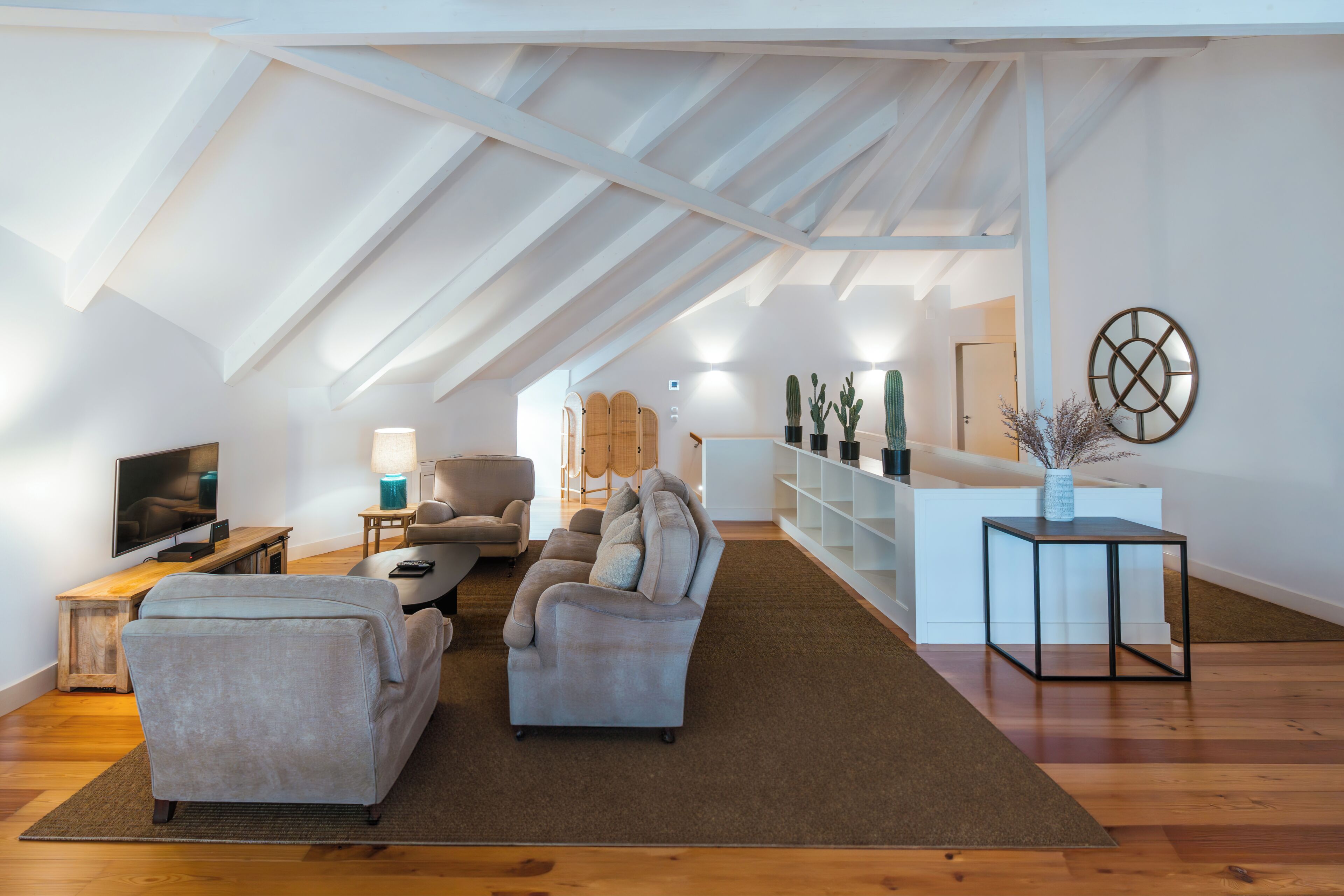 Un loft espacioso con techo alto, un conjunto de sofás, un televisor y una estantería.