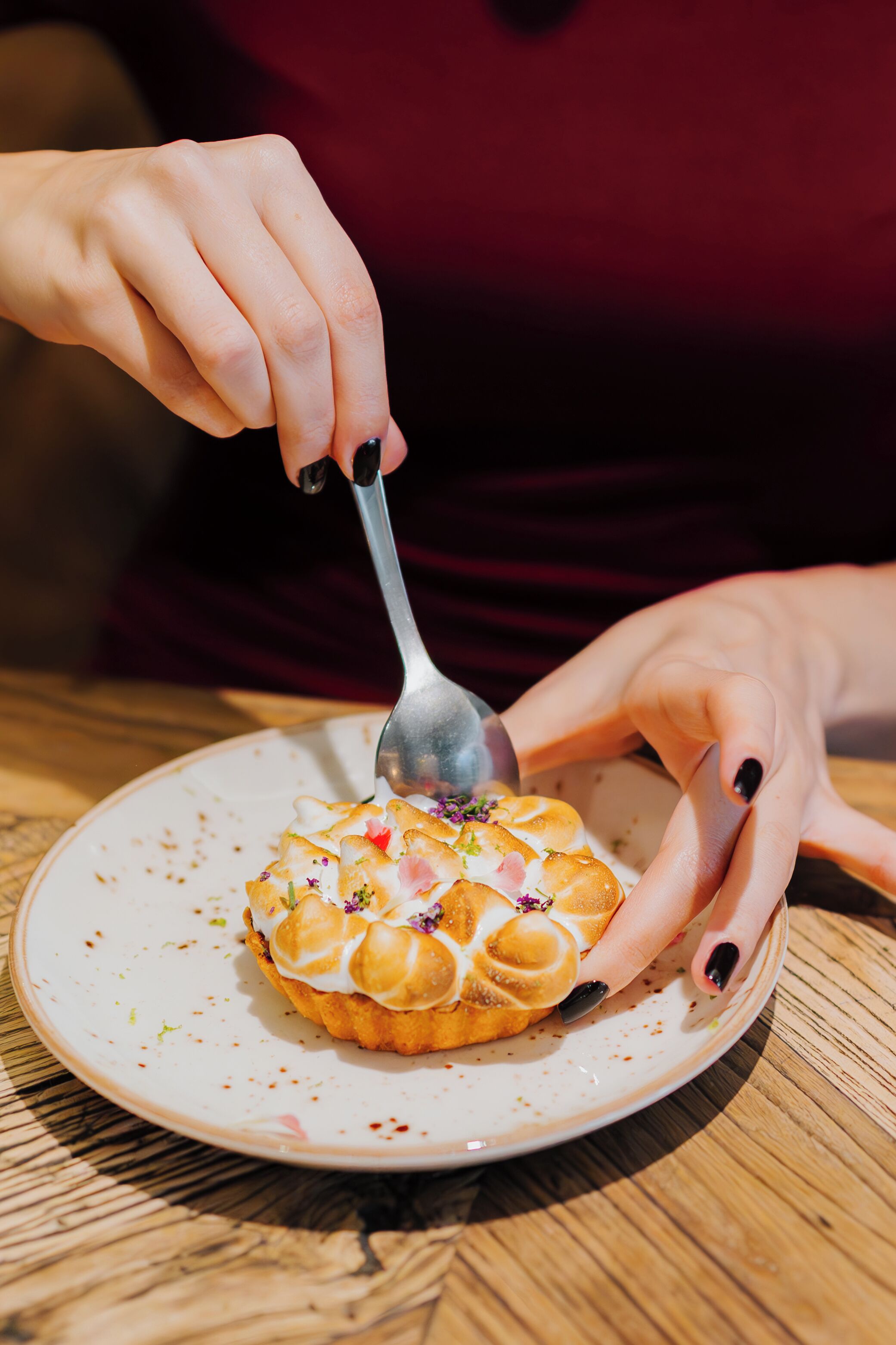 Una persona tiene un cucchiaio sopra un dolce su un piatto.