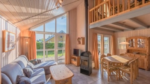 A cozy cabin interior with a wooden interior, a sofa, a dining table, and a fireplace. - Ferienpark Mueritz (Rechlin)