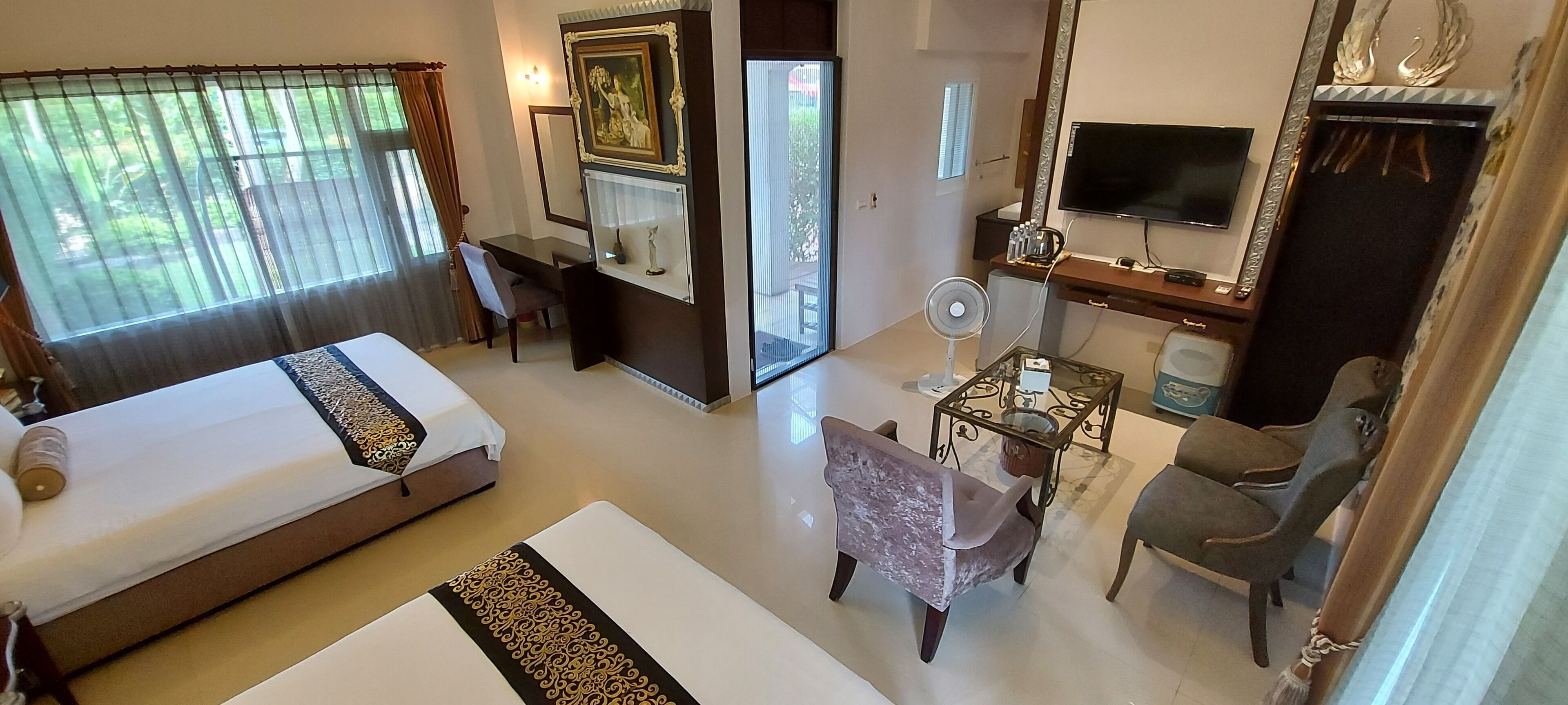 A hotel room with a bed, a desk, a chair, a TV, and a mirror.