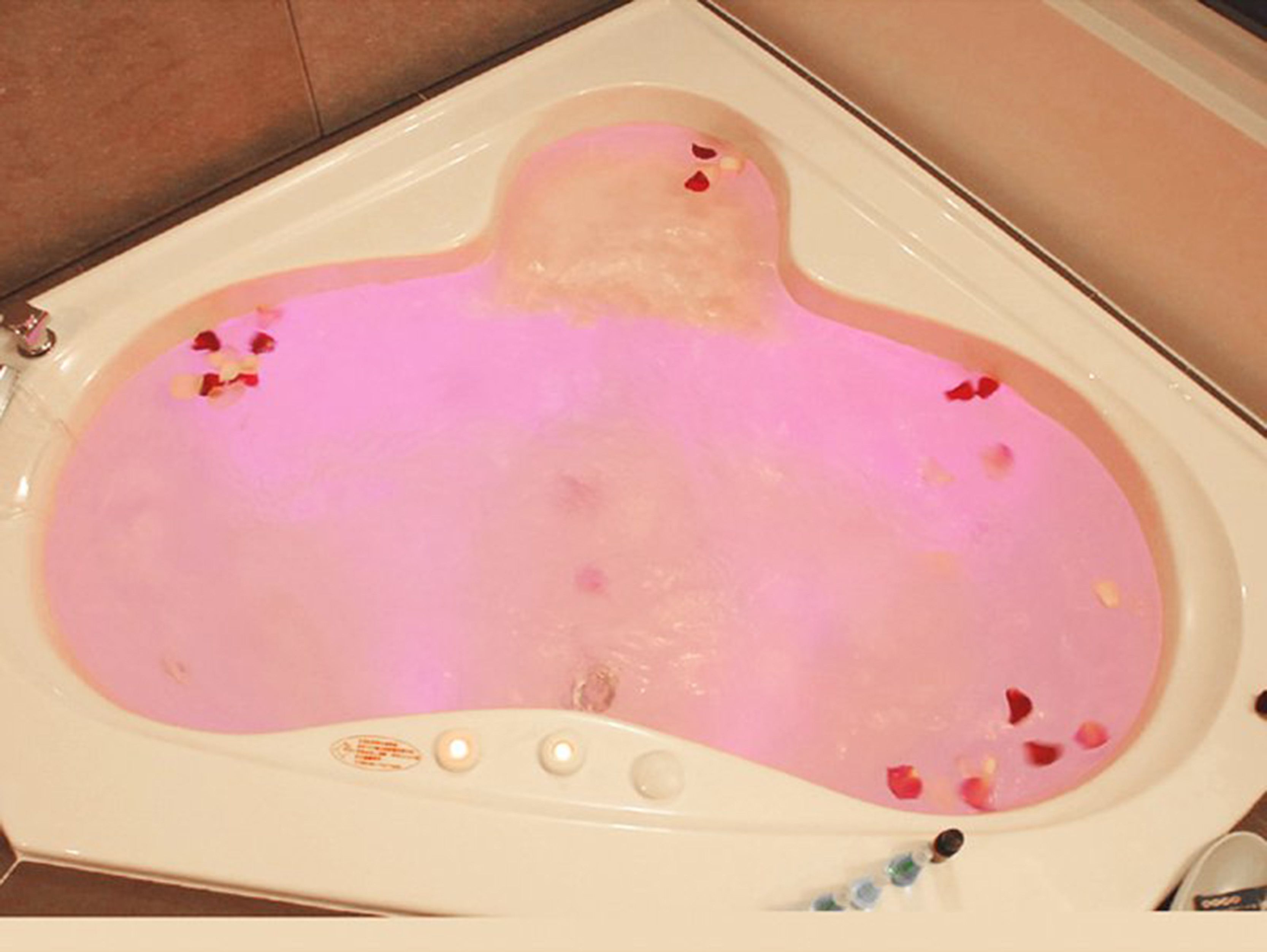 A bathtub filled with pink water and rose petals.