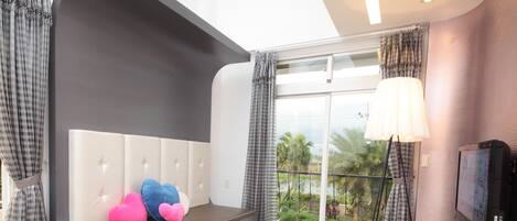 Una sala de estar moderna con un sofá, una mesa de centro de vidrio, un tapete a rayas y un televisor en la pared.