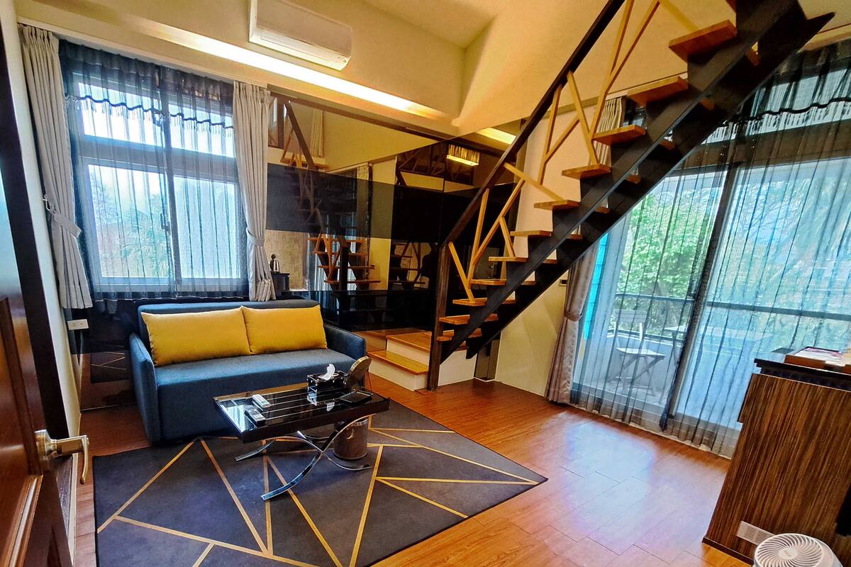 A modern living room with a sofa, coffee table, and a staircase.