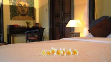 Una cama con un arreglo floral, un cuadro de Buda y una lámpara en una habitación de hotel.