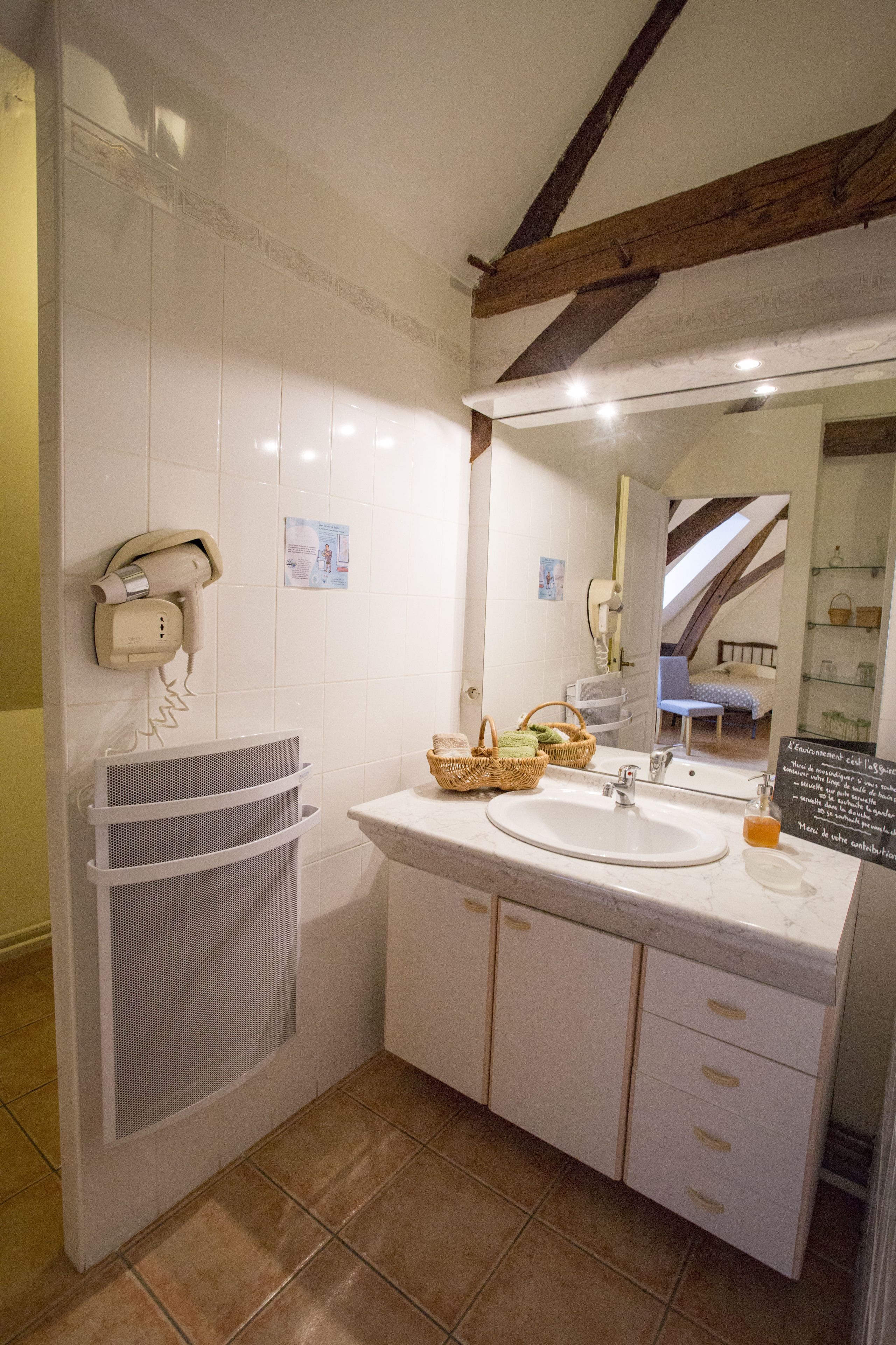 A bathroom with a sink, mirror, and a hairdryer mounted on the wall.