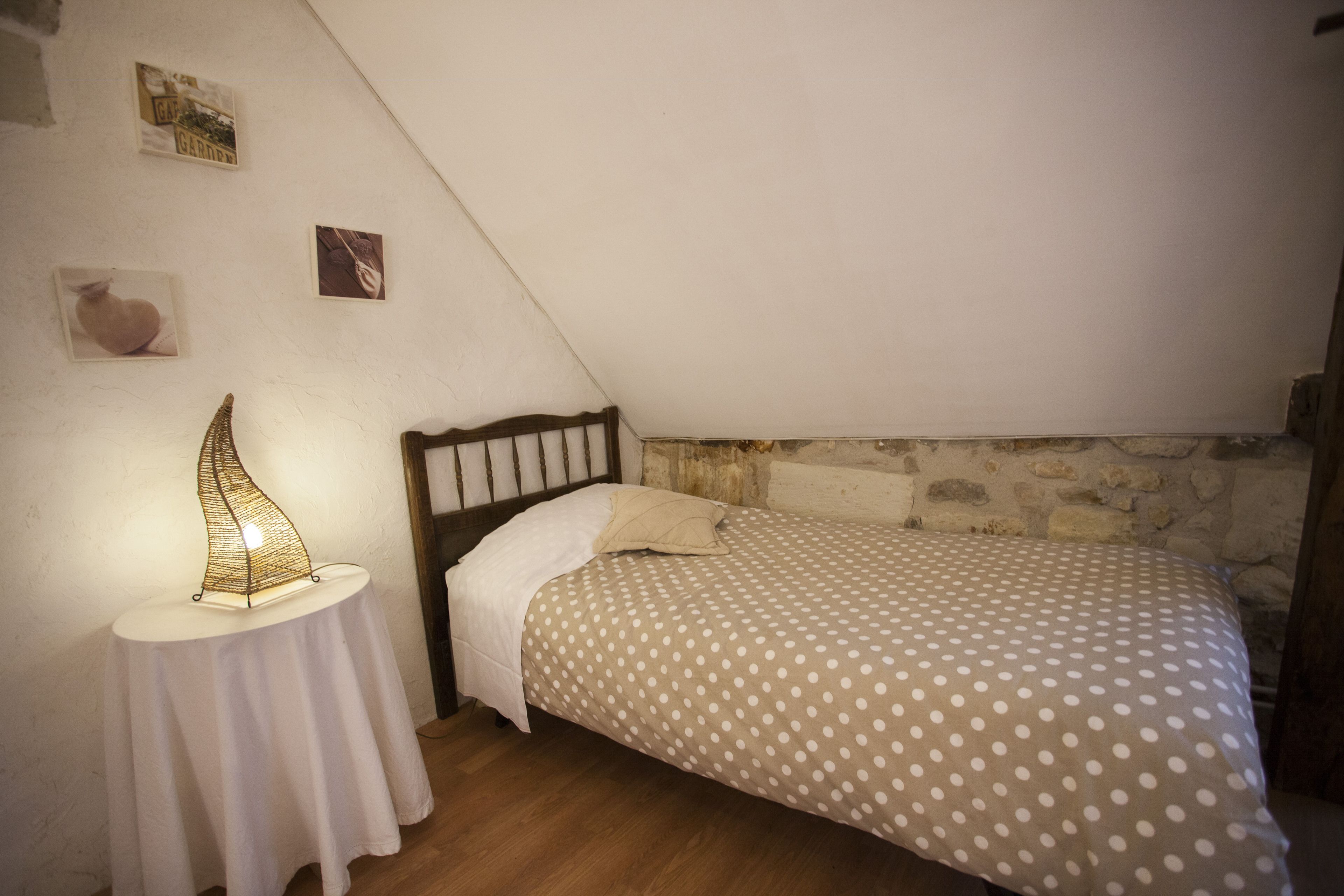 A bedroom with a bed, a bedside table with a lamp, and a polka dot bedspread.