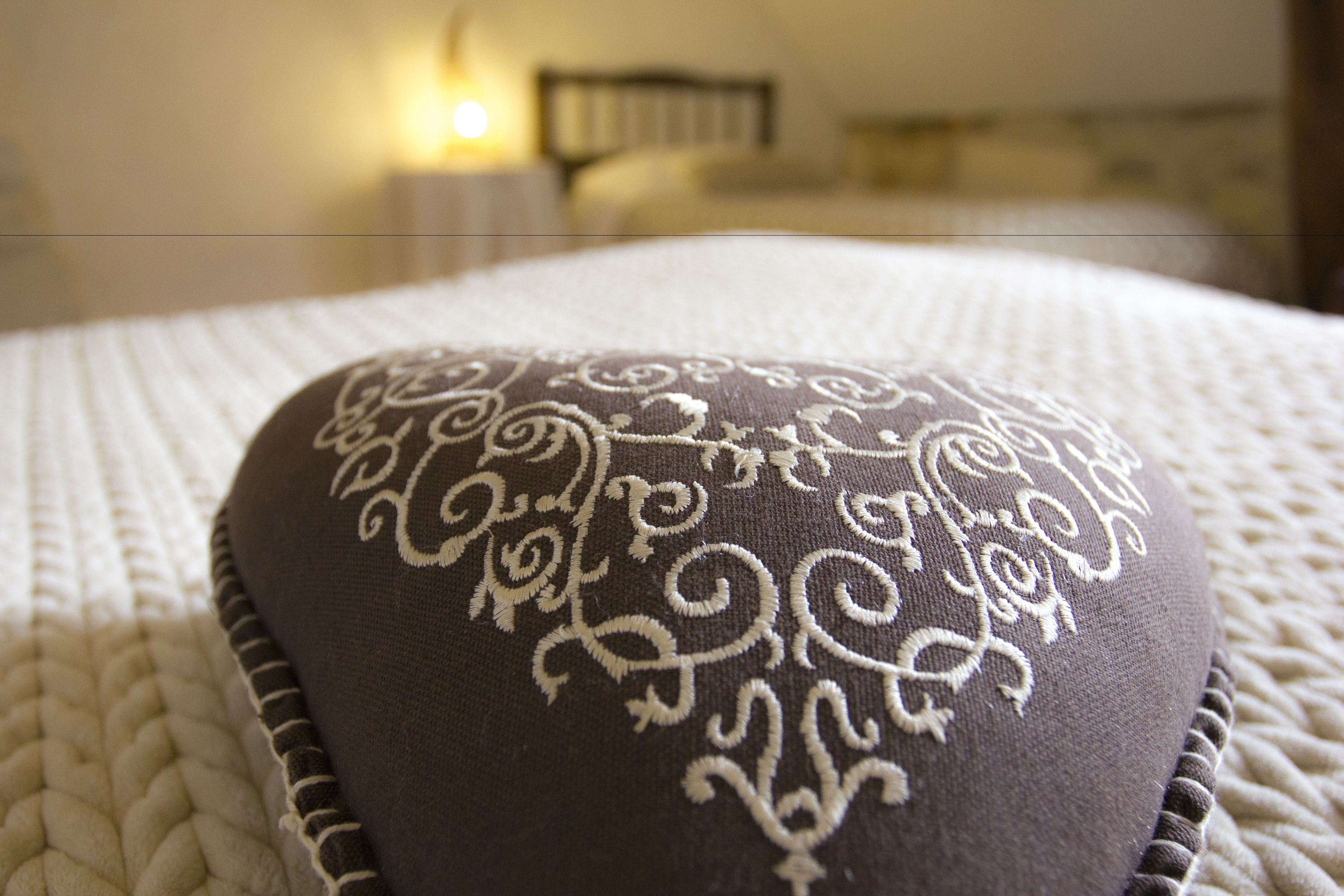 A close-up of a pillow with a decorative pattern on a textured bedspread.