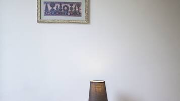 A wooden table with a lamp and a chair in front of it. There are two framed pictures on the wall above.