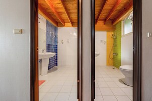 Un baño con piso de baldosas, un lavamanos, un inodoro y una zona de ducha.