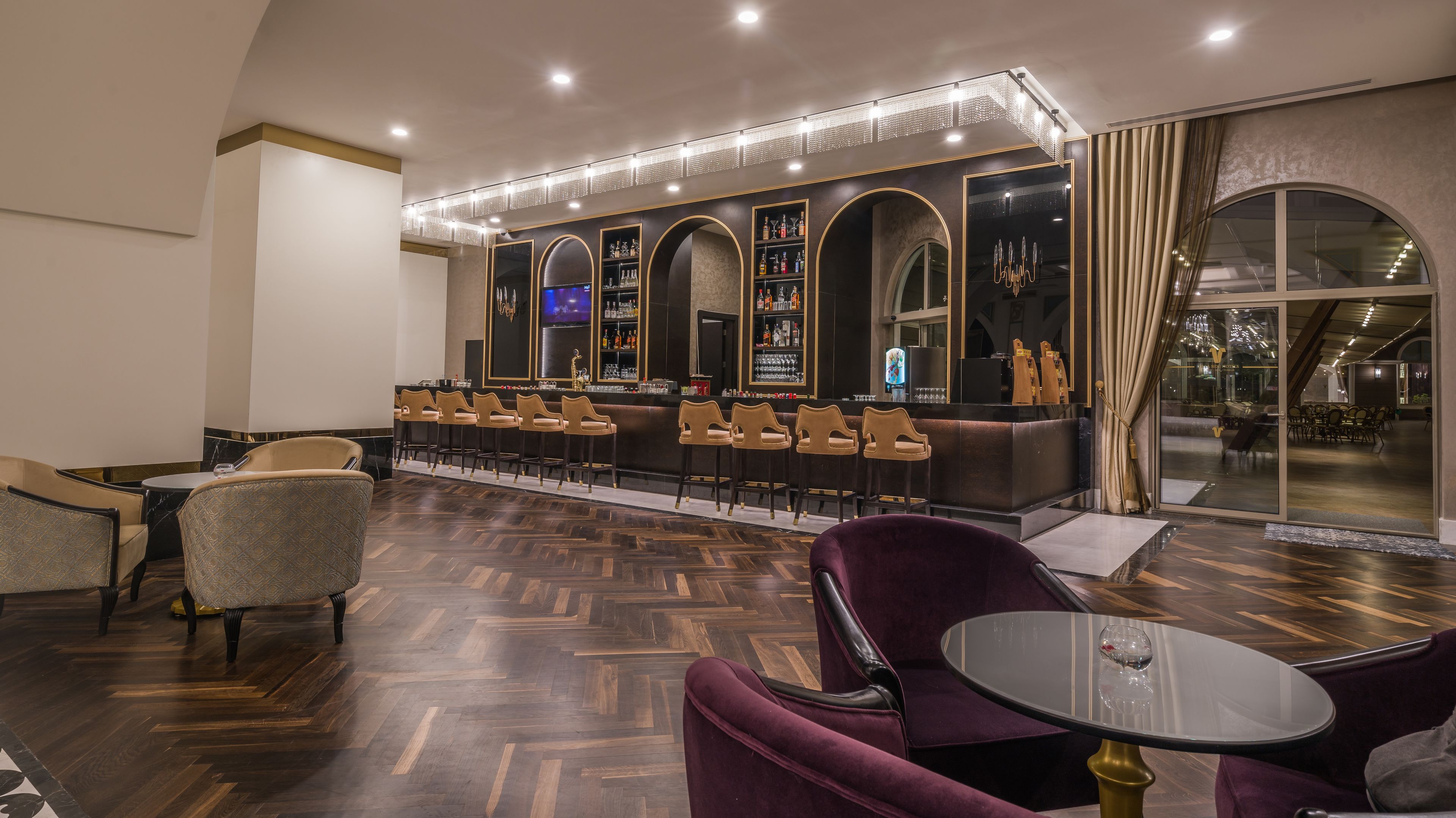 Un espace bar doté d’un long comptoir, de nombreux tabourets et d’un coin salon avec des fauteuils confortables et une table ronde.