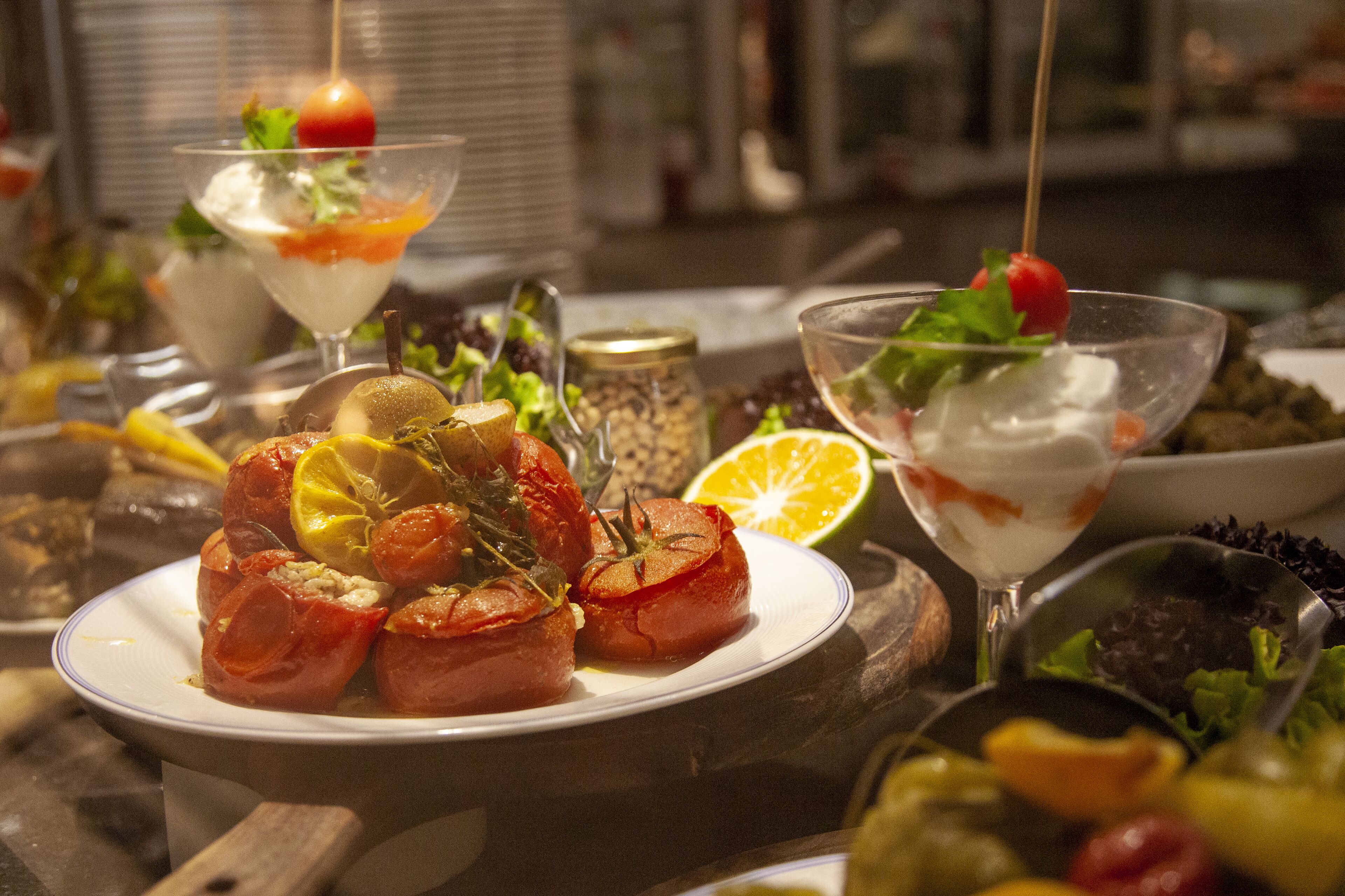A table with various dishes, including stuffed tomatoes and a salad with a cherry tomato garnish.