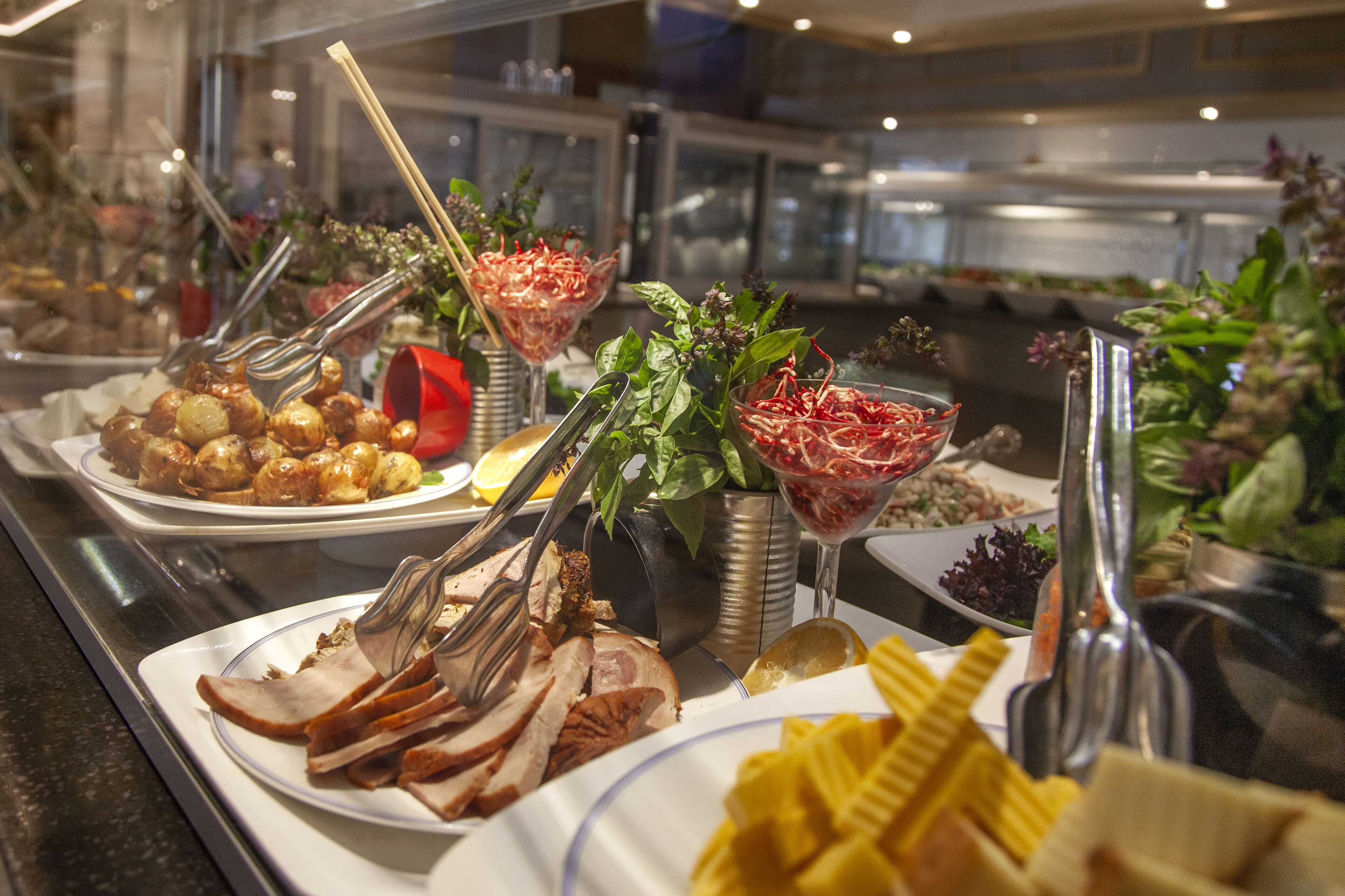 Un bufé con diversos platos, entre ellos carnes en rodajas, ensaladas y guarniciones.
