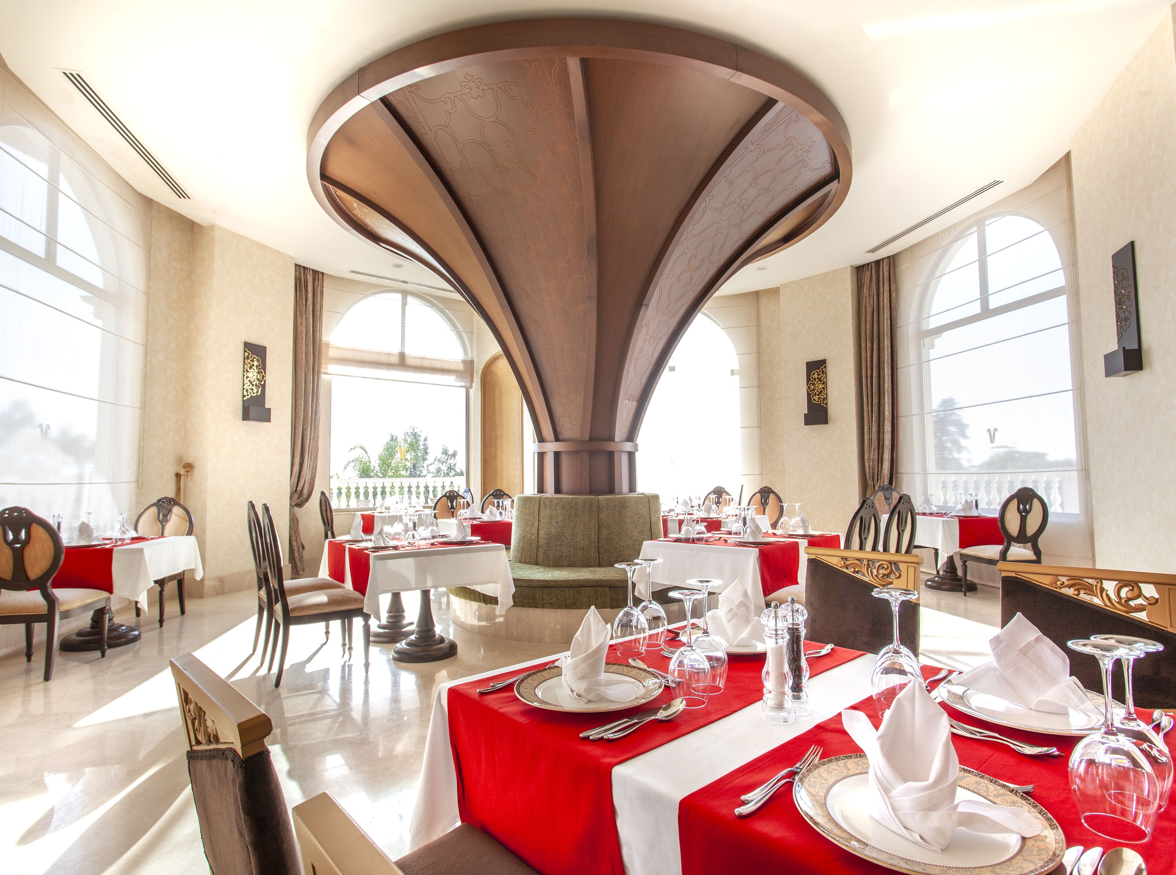 A dining area with tables set for service, large windows, and a central architectural feature.