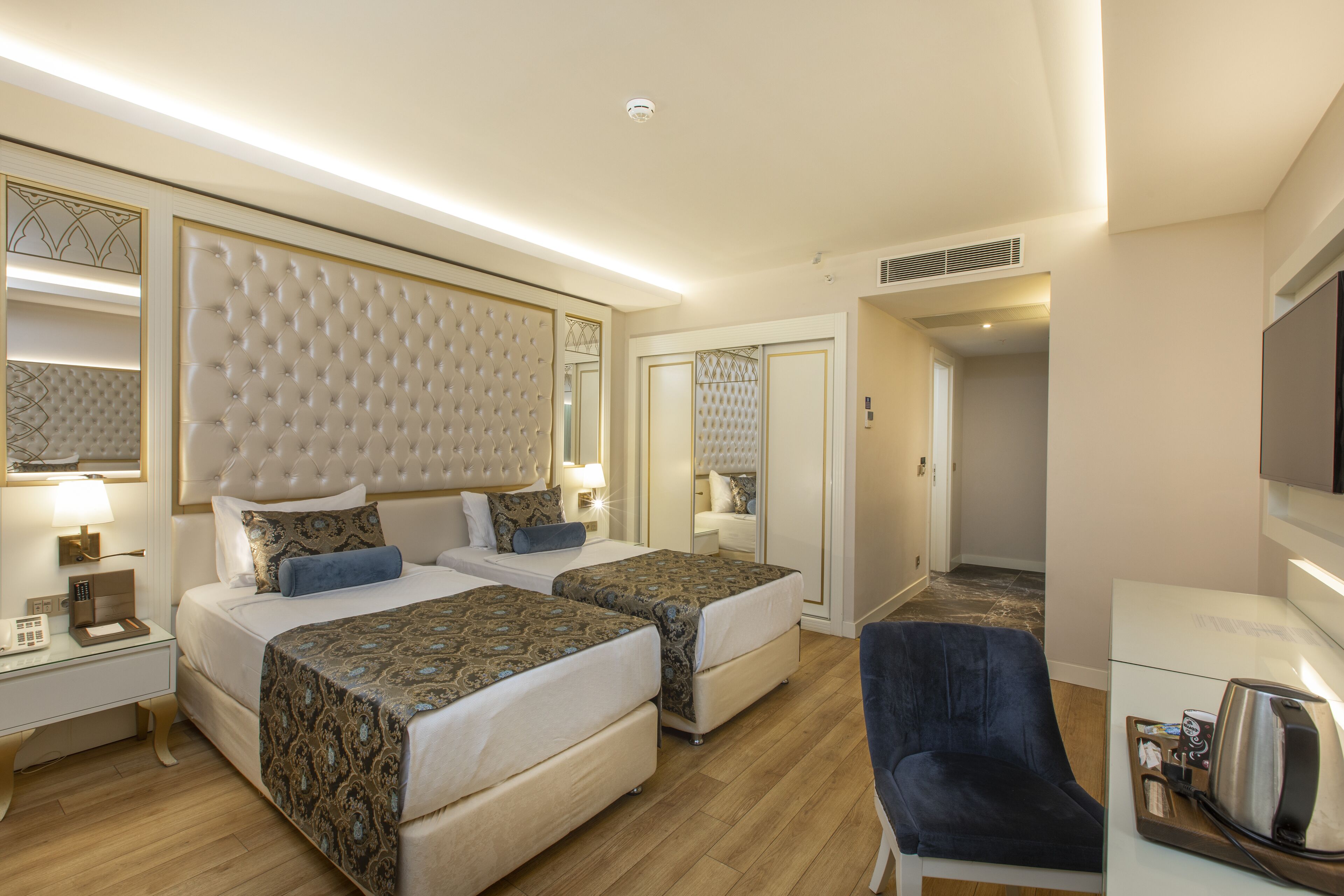 Ein Hotelzimmer mit zwei Betten, einem Schreibtisch, einem Stuhl und einem Fernseher.
