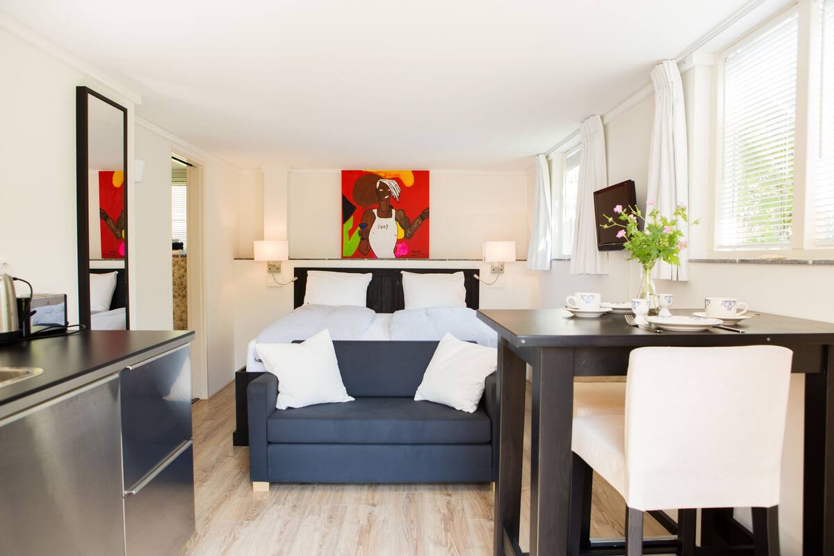 Habitació d'hotel moderna amb llit, escriptori, cadira i taula de menjador.