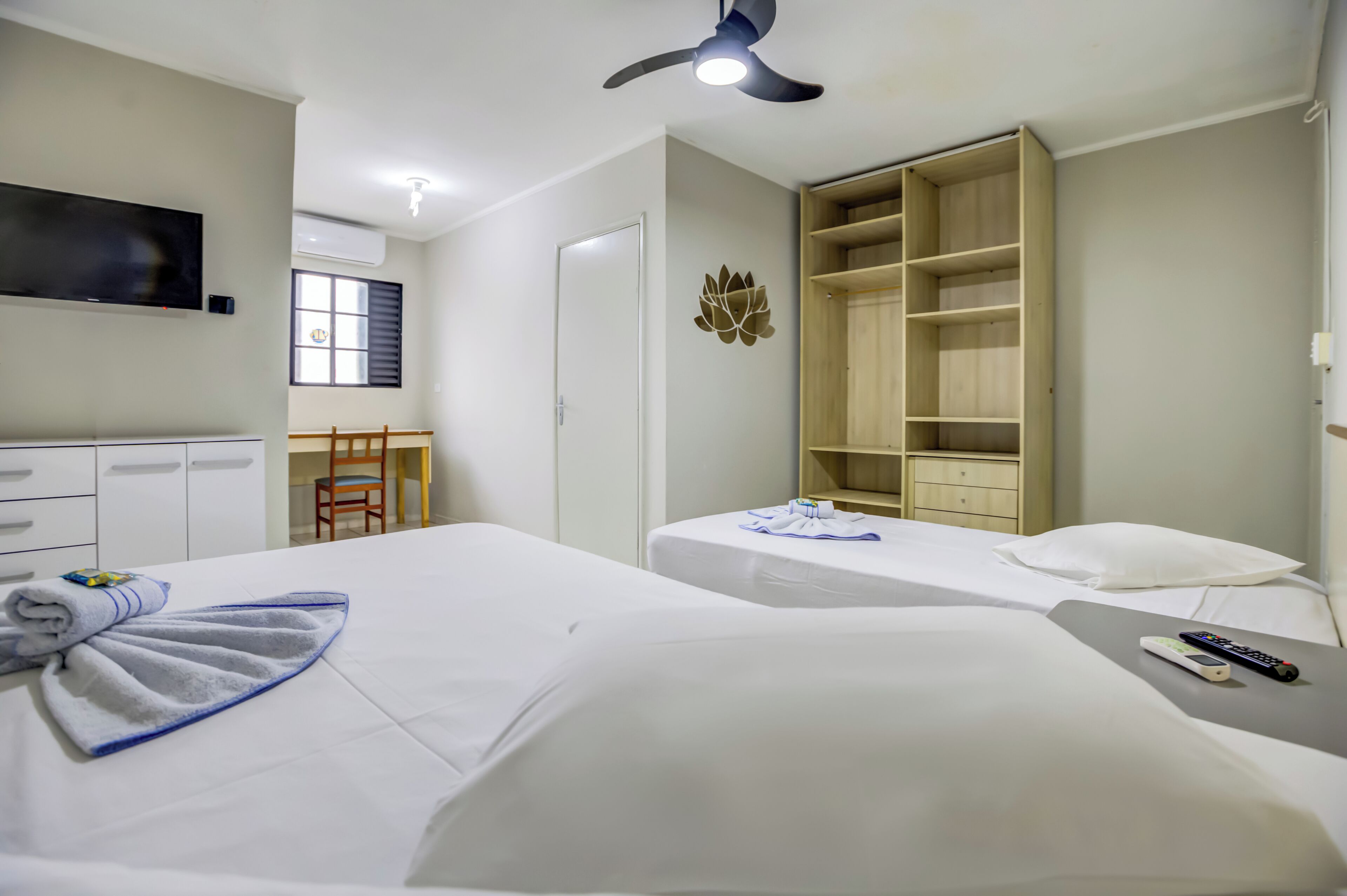 Habitación de hotel con dos camas, televisión, armario y escritorio con silla.