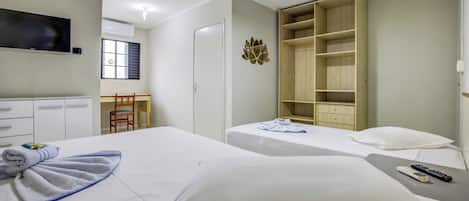 A hotel room with two beds, a TV, a wardrobe, and a desk with a chair.