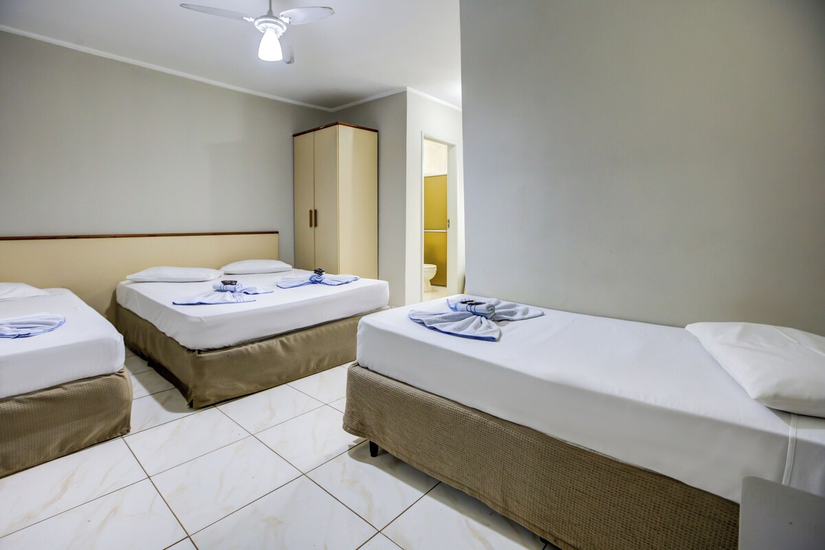 A hotel room with two beds, a wardrobe, and a ceiling fan.