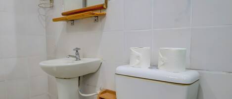 A bathroom with a white toilet, a pedestal sink, and a mirror with a wooden frame.