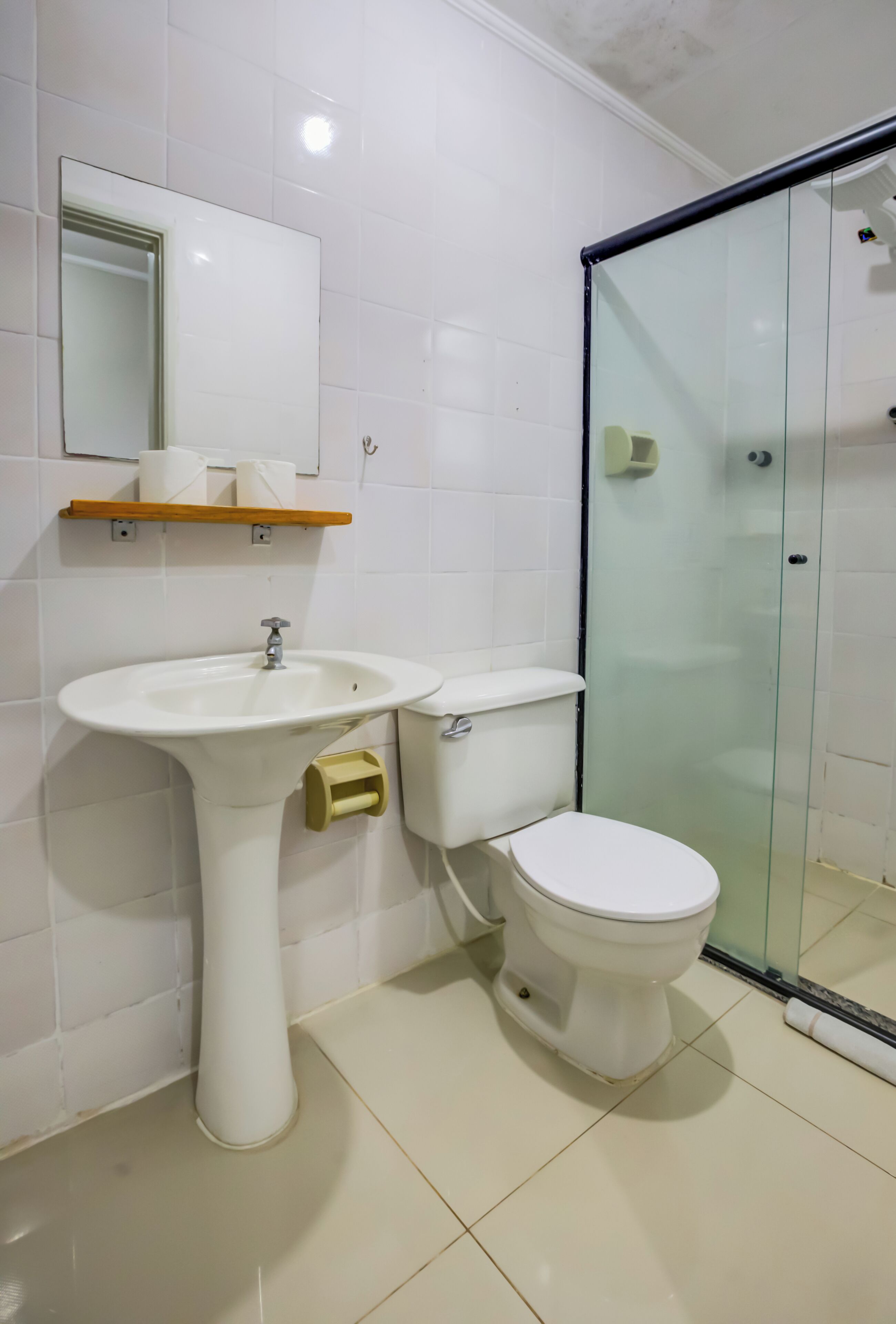 A bathroom with a pedestal sink, toilet, and a glass shower enclosure.