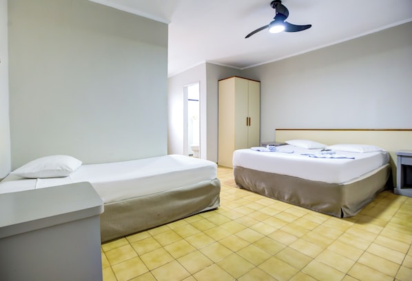A hotel room with two beds, a wardrobe, a ceiling fan, and a tiled floor.