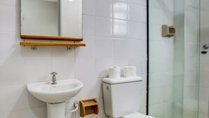 Ein Badezimmer mit weißem Waschbecken, Spiegel, Toilette und Duschkabine aus Glas.