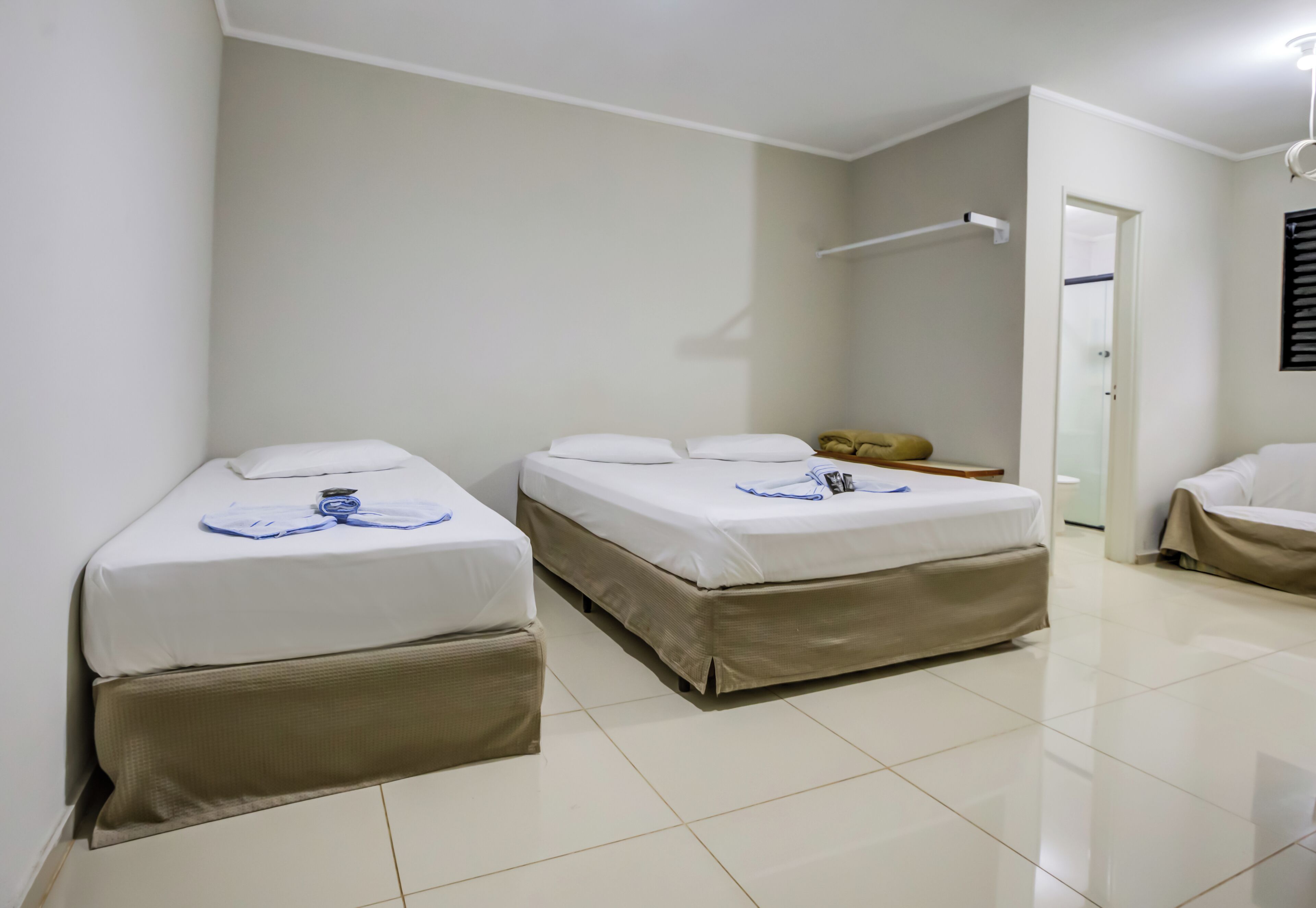 Quarto de hotel com duas camas, uma mesa pequena e porta para um banheiro.