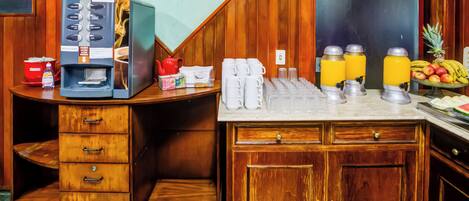 A kitchen area with a coffee machine, a fruit bowl, and a refrigerator.