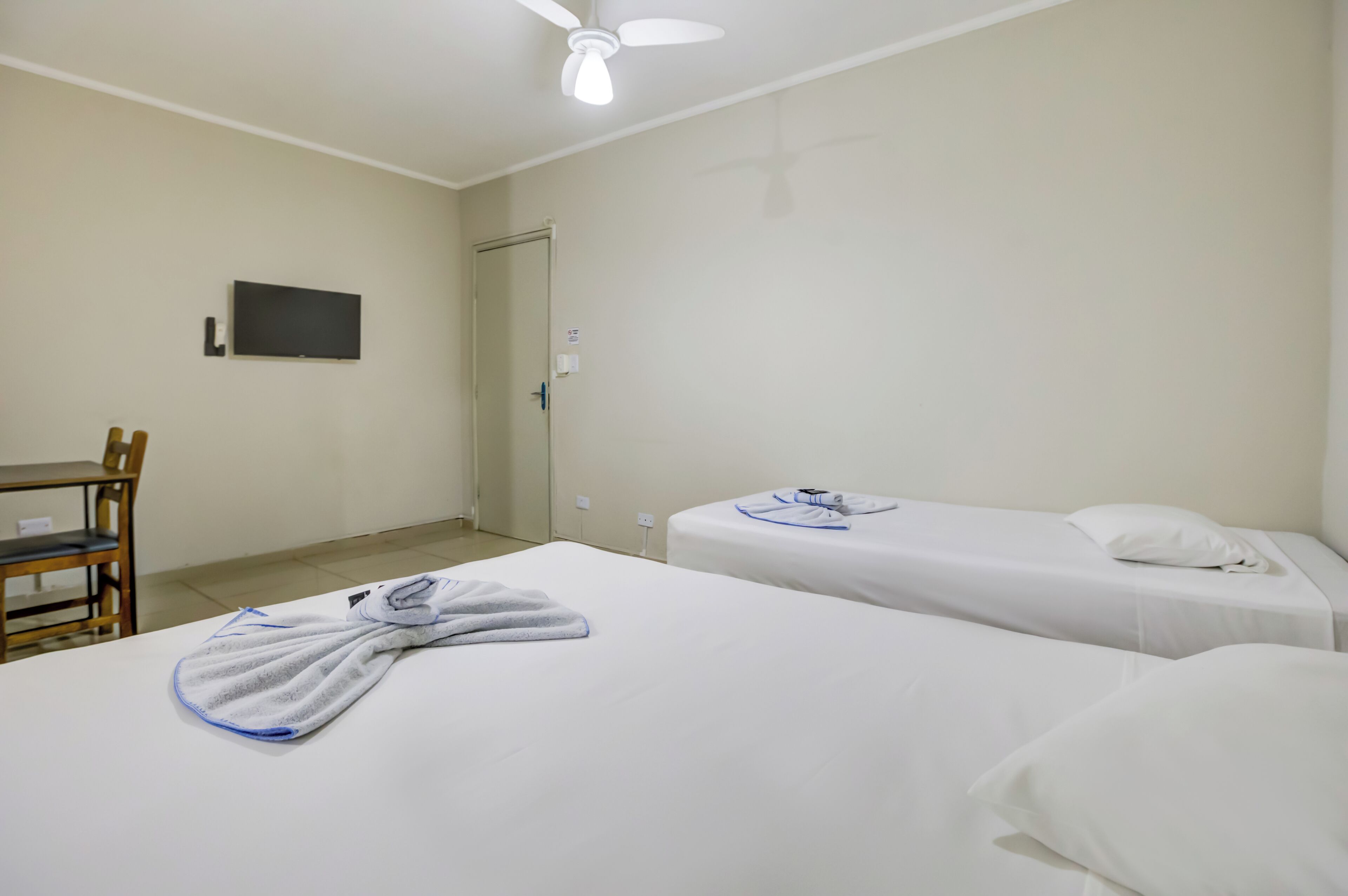 Une chambre d’hôtel avec deux lits, un bureau et une télévision.