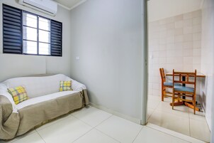 A room with a sofa, a chair, and a window with blinds.