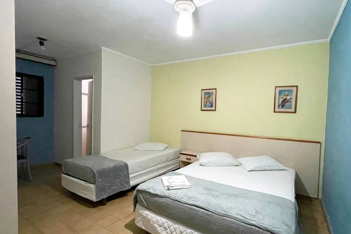 Ein Zimmer mit zwei Einzelbetten, einem Deckenventilator und einer Tür zu einem weiteren Zimmer.