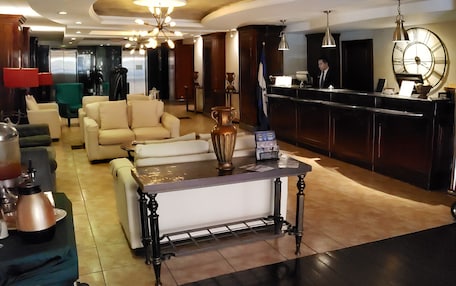 A hotel lobby with a reception desk, seating area, and a large clock.