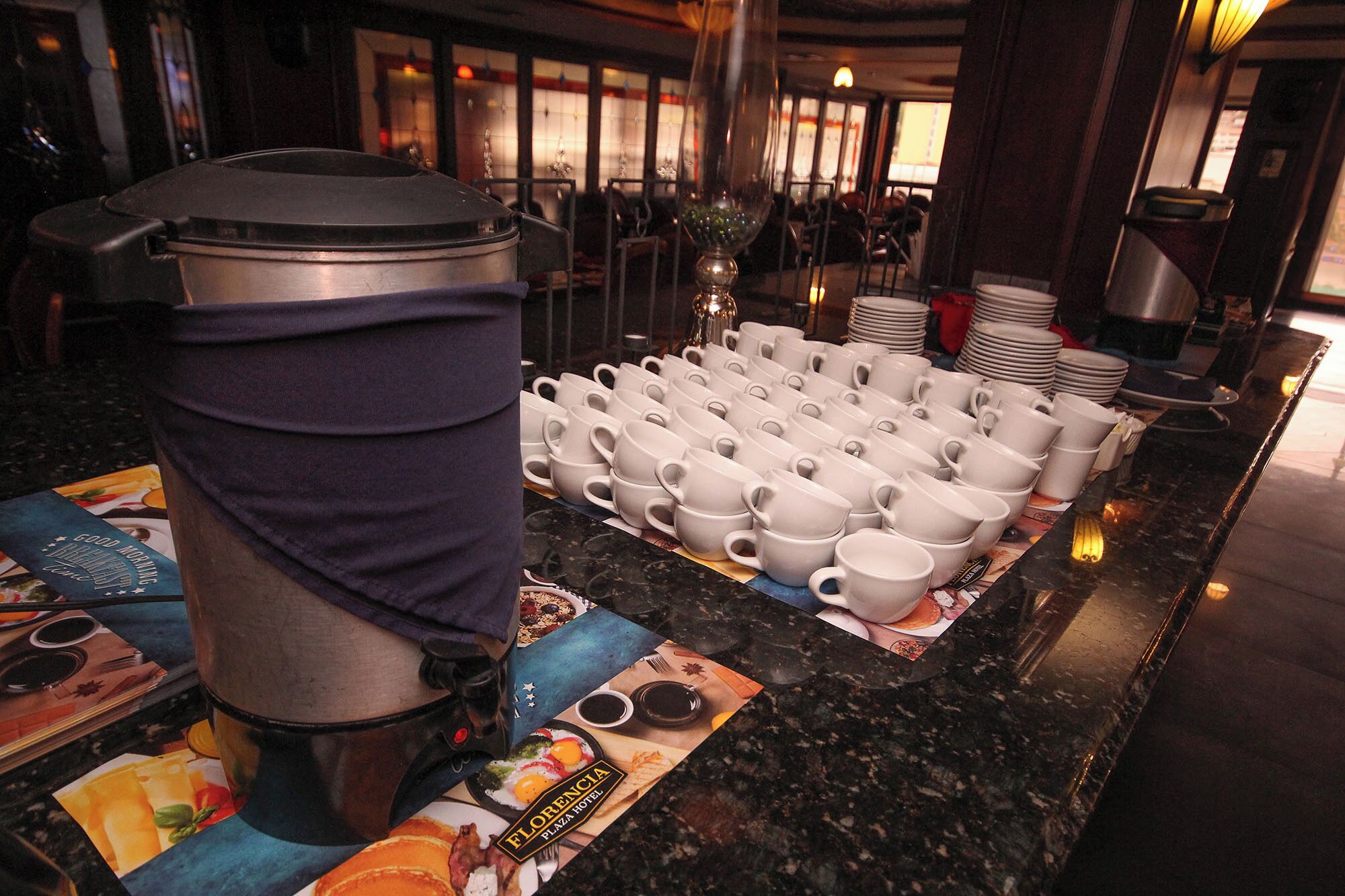 Ein reichhaltiges Buffet mit einer Kaffeemaschine und mehreren weißen Tassen auf einer Theke.