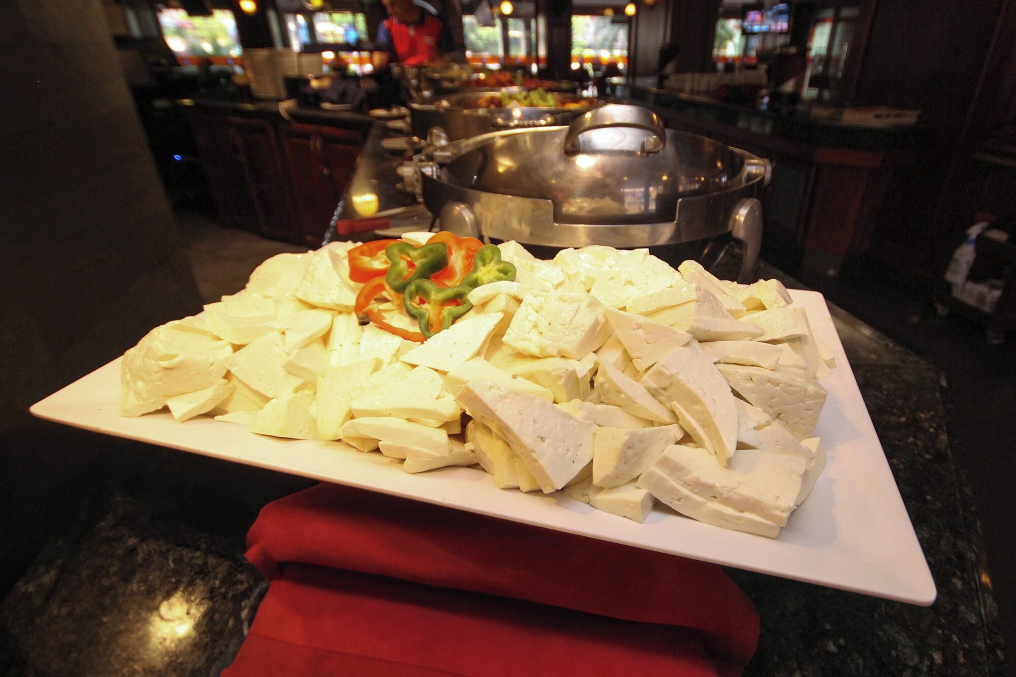 A buffet table with a variety of food items, including tofu and vegetables, in a restaurant setting.