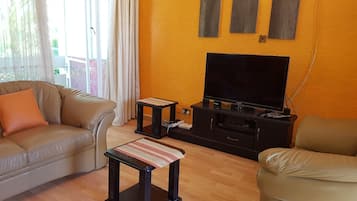 A living room with a sofa, a coffee table, a TV on a stand, and a chair.