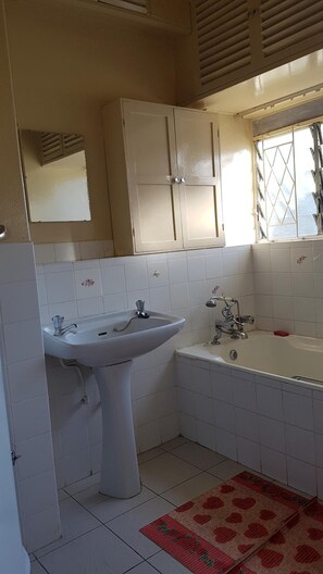 Un baño con lavamanos, bañera y ventana.