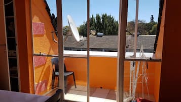 A balcony with a chair, a satellite dish, and a metal drying rack.