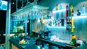 A bar area with a counter, shelves with bottles, hanging glasses, and a variety of bar equipment. - All Inn Hotel (Istanbul)