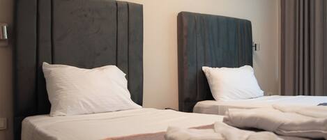 Habitación de hotel con dos camas, cada una con cabecera y almohadas blancas.